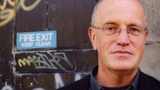Image of Iain Sinclair standing in front of a graffitied door