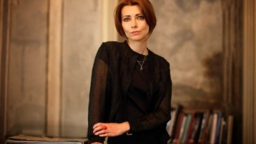 Image of Elif Shafak leaning against a wooden cabinet in an old stone building
