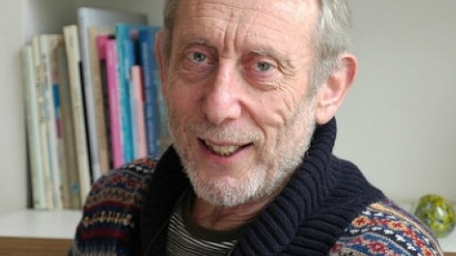 Image of Michael Rosen in a colourful fairisle jumper, sitting in front of book shelves
