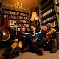 A picture of the musical trio the bookshop band reading a book