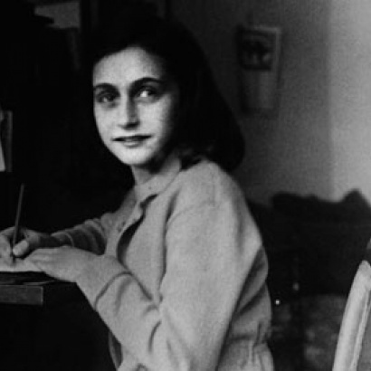 Photograph of a young Anne Frank writing at her desk