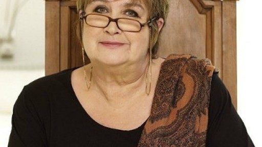 Image of Jenni Murray sat in chair with brown scarf over one shoulder