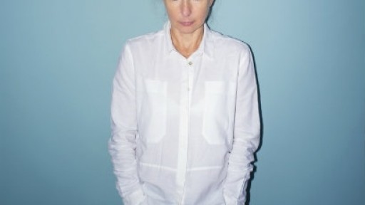 Image of Lionel Shriver in a white shirt in front of a blue background