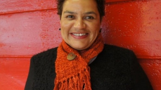 Image of Jackie Kay in orange scarf in front of red wooden slats