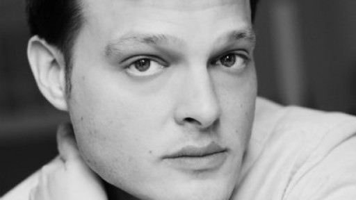 Image of Garth Greenwell with his arms crossed and one hand on the side of his neck