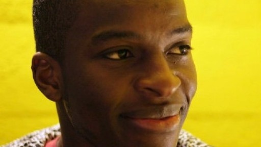 Image of Kayo Chingonyi smiling off camera in front of a yellow background
