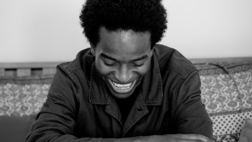 Zambian born, British based poet smiling on a sofa