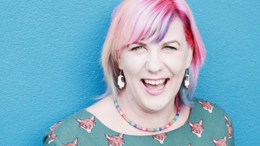 Comedian and poet Kate Fox against a bright blue wall