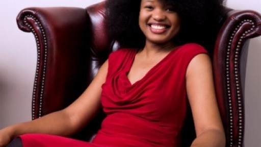 Image of Chibundu Onuzo in a bright red dress, sitting in a leather armchair