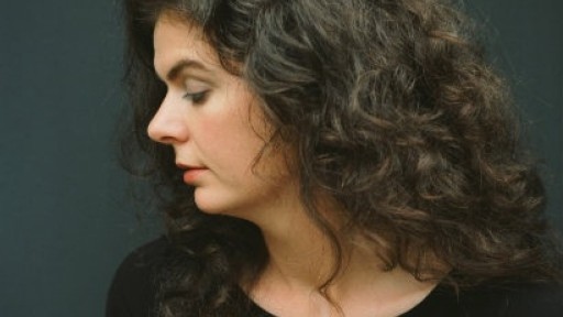 Image of Tara Bergin with her head to the side, with long, curly brown hair