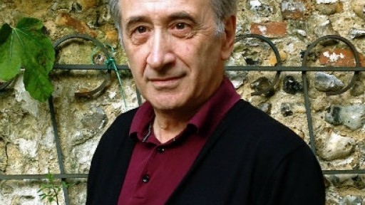 Image of George Szirtes in front of a fig tree growing up an old stone wall