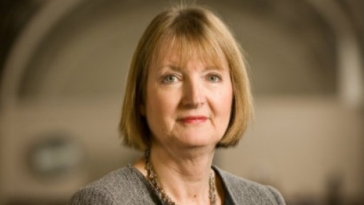 Image of Harriet Harman in a smart grey jacket with a black collar, standing in a large library
