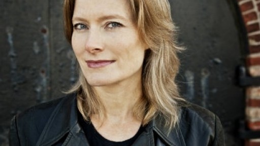 Jennifer Egan in a black leather jacket, standing in front of a brick archway