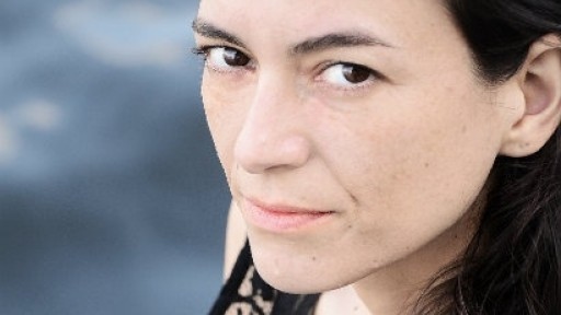 Close-up image of Samanta Schweblin, wearing a black lace top, and looking up into the camera