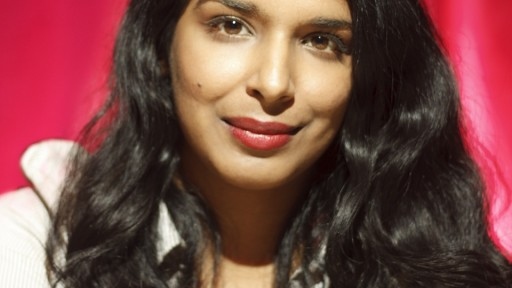 Colour photo of arts journalist & author Anita Sethi against a pillarbox red backdrop