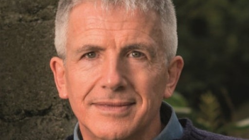 Head and shoulders shot of author Patrick Gale, standing in front of a tree