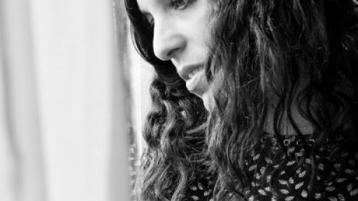 Black and white image of author Ariana Harwicz, taken from the side, looking out of a window