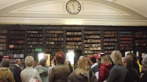Image of people listening to tour guide in front of bookcases