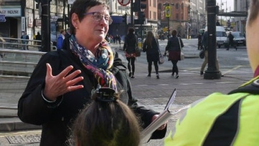 Image of walking tour guide, Anne Beswick, talking to tour participants in central Manchester