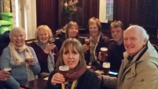 Image of tour participants seated in corner of pub, all raising their glasses