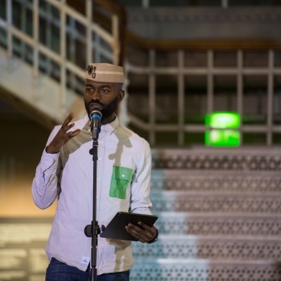 Photo of poet Inua Ellams on stage at Manchester Museum
