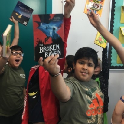 Image of a young boy holding up a book he received from the Book Trust