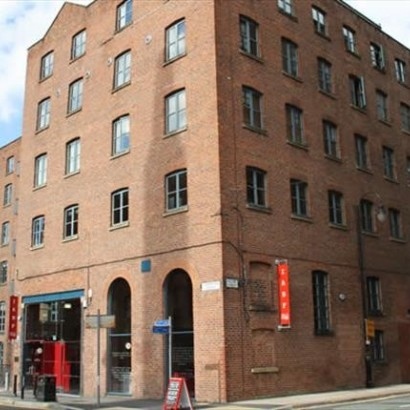 Photograph of the red brick mill that includes the International Anthony Burgess Foundation and its distinctive red signage