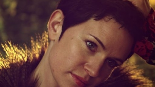 Close-up portrait of award-winning author Sarah Hall with dark cropped hair and a big, fur-lined coat.